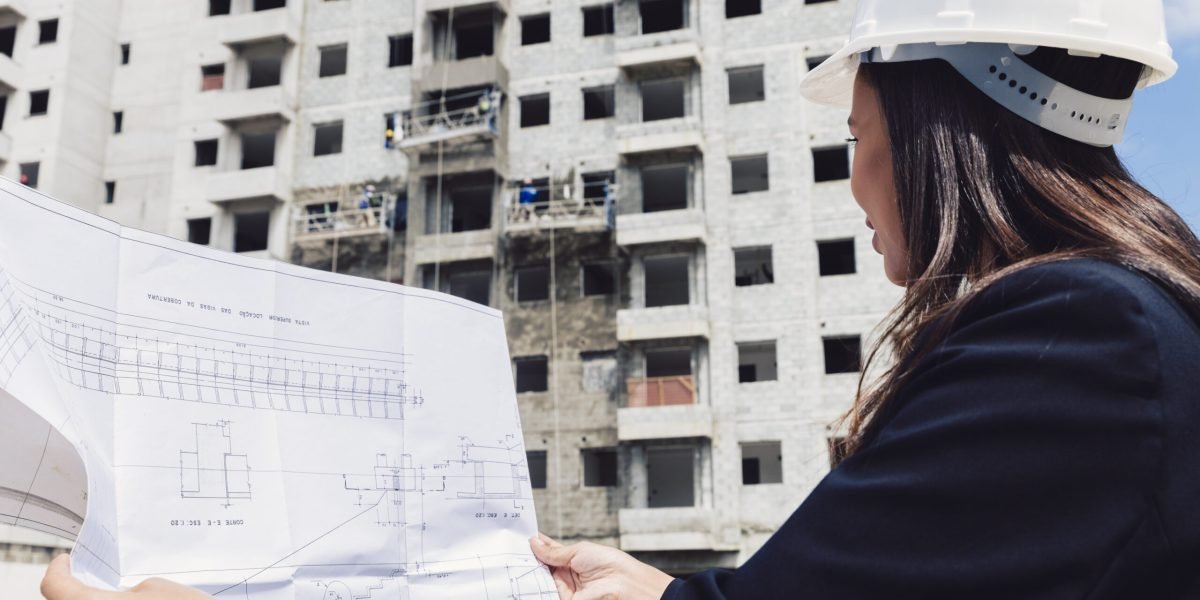 african-american-lady-safety-helmet-with-paper-plan-near-building-construction